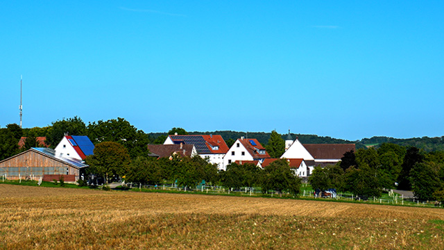 Blick auf Talheim, umgeben von Stoppelfeldern und landwirtschaftlichen Gebäuden.